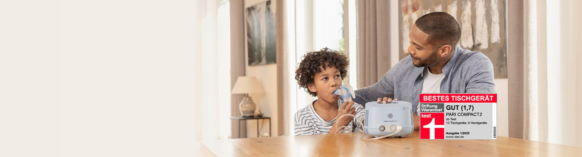 Ein Kind inhaliert mit einem blauen PARI COMPACT2 Inhalator, während der Vater unterstützend daneben sitzt. Stiftung Warentest Bewertung: Gut (1,7).