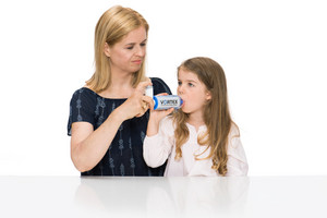 Mutter hilft Tochter bei der Inhalation von Asthmaspray mit Inhalierhilfe