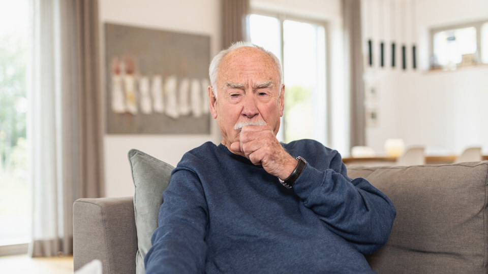Painful cough: What can you do? 10 helpful tips to help your cough hurt less Elderly man sitting on the couch and coughing in his fist
