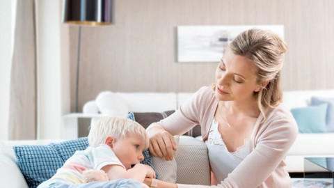 What can I do if my child is always coughing? Interview with Prof. Carl-Peter Bauer Junge liegt krank auf der Couch, Mutter tröstet ihn