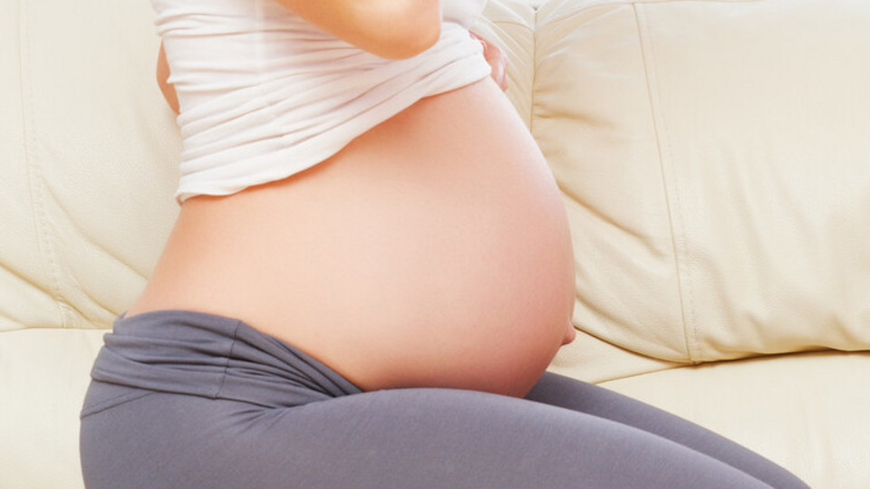 Conceiving and pregnancy with cystic fibrosis: a case report Schwangere Frau kniet auf dem Sofa