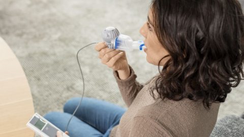 Erfahrungsbericht: eFlow®rapid Inhalationssystem mit eTrack® Controller und PARI Connect® App Aufnahme einer jungen Frau seitlich von hinten, die mit dem eFlow rapid Inhalationssystem mit eTrack Controller inhaliert