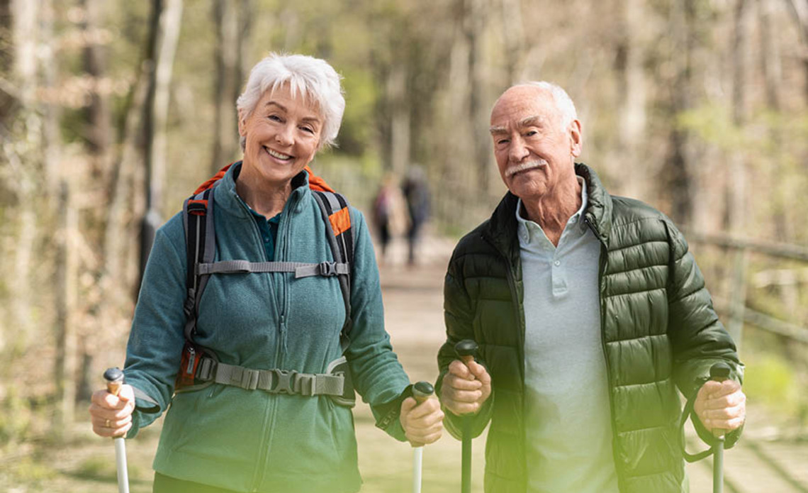 Everyday measures – lung sport, for example Two older adults walking outdoors with trekking poles