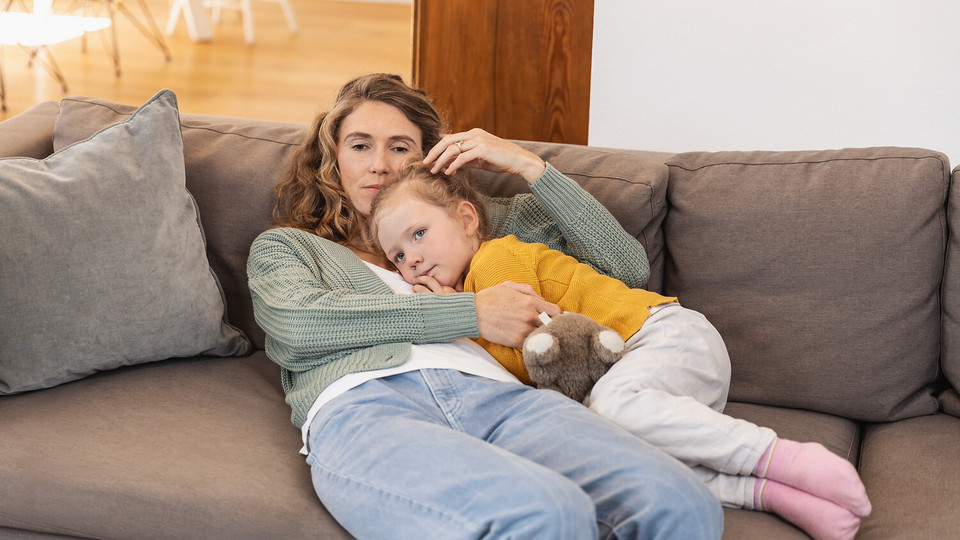 Your child has a cold: What can you do? 8 useful tips to help your child through a cold Mother cuddling sick daughter on the couch