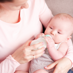 Nahaufnahme von Baby im Arm der Mutter, sie gibt ihm ein Fläschchen