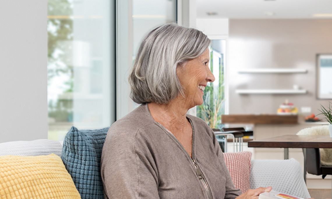 Nebuliser therapy for chronic obstructive pulmonary disease Person with gray hair sitting on a sofa in a bright living room, holding a book or tablet