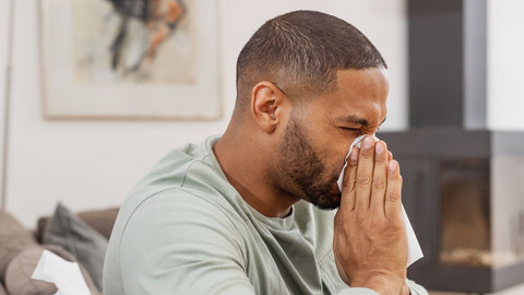 Quickly get rid of a cold? How to help a blocked nose Young man is blowing his nose