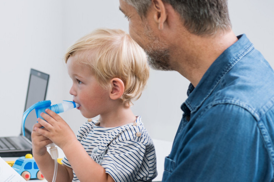 Games for children to expel mucus from the lungs: Best time Father has his young son on his lap, who is inhaling with a nebuliser