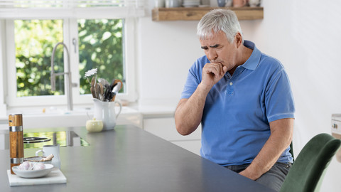 Stopping the urge to cough: 8 tips that can help you manage a coughing fit Elderly man sitting in the kitchen while coughing