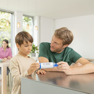 Vater und Sohn sitzen am Küchentisch und bauen die VORTEX Inhalierhilfe zusammen