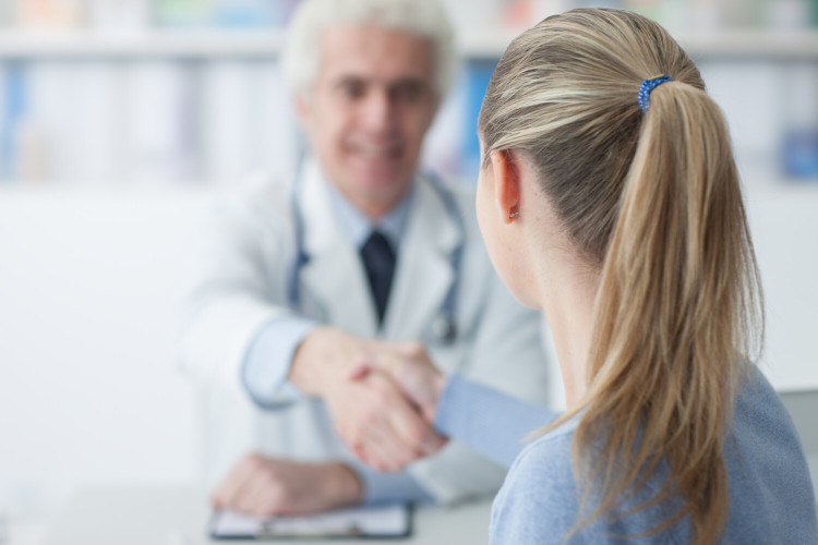 Pregnancy with cystic fibrosis: at the doctor's office Elderly doctor shakes hands with young patient across desk