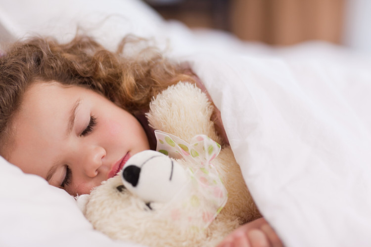 Tips when your child has a cold: Sleep Little girl with a cold lies asleep in bed with teddy bear in her arms