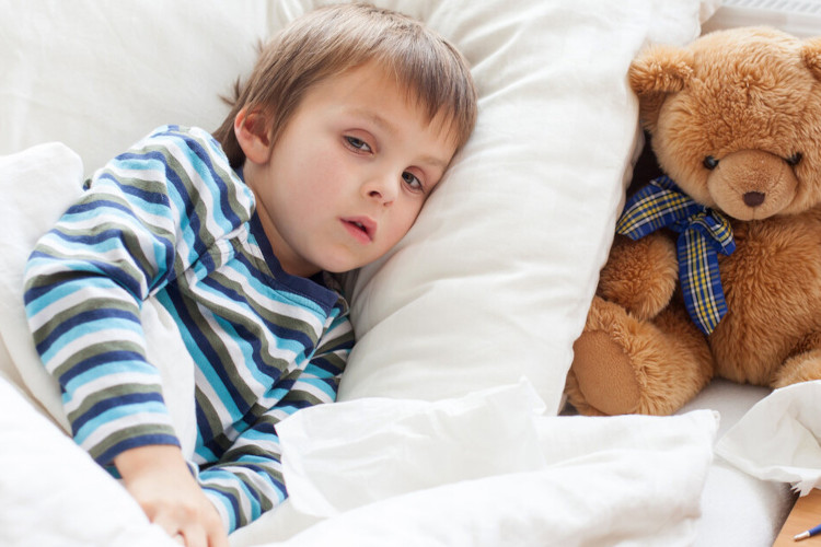 Coughing in children: Painful cough Small child lying ill in bed, teddy bear sitting next to the pillow