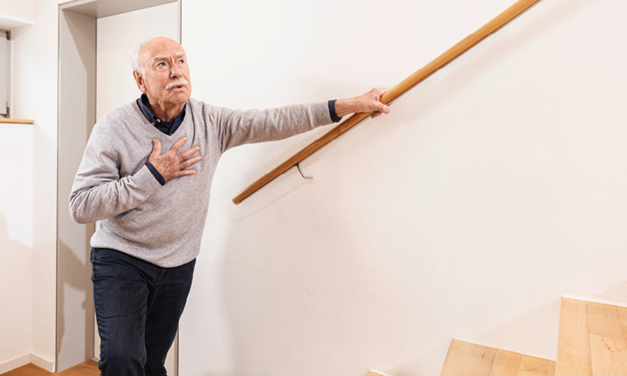 A man with bronchitis touches his chest while climbing stairs