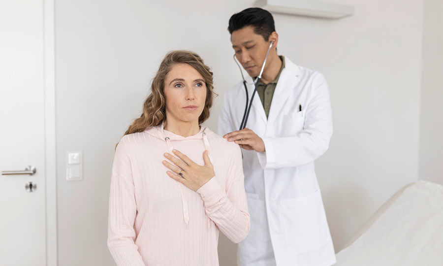 Doctor examines patient with cystic fibrosis. Patient has her hand on her chest.