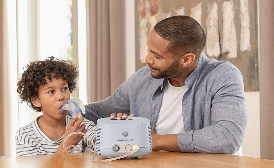 A little boy has an RS virus infection and therefore inhales with the COMPACT2, his father sits next to him