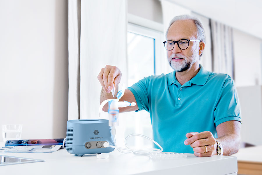 Man sits on the chair and fills the nebulizer with saline solution.