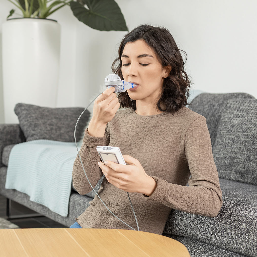 A young woman inhales with the PARI eFlow rapid and holds the eBase Controller in her hand Young-Lady-inhales-with-eFlow-rapid-and-uses-eBase-Controller.jpg