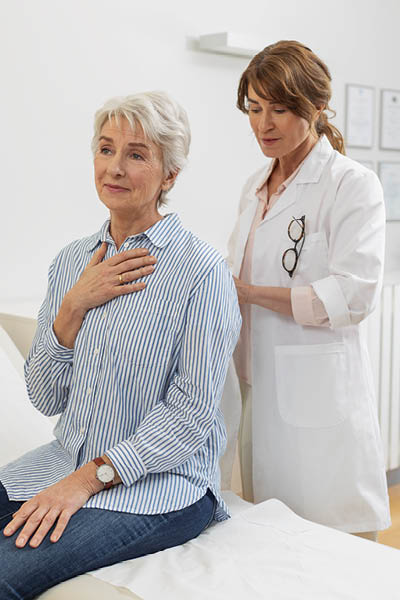 Respiratory diseases A doctor examines a seated person and places a stethoscope against their back for a medical examination.